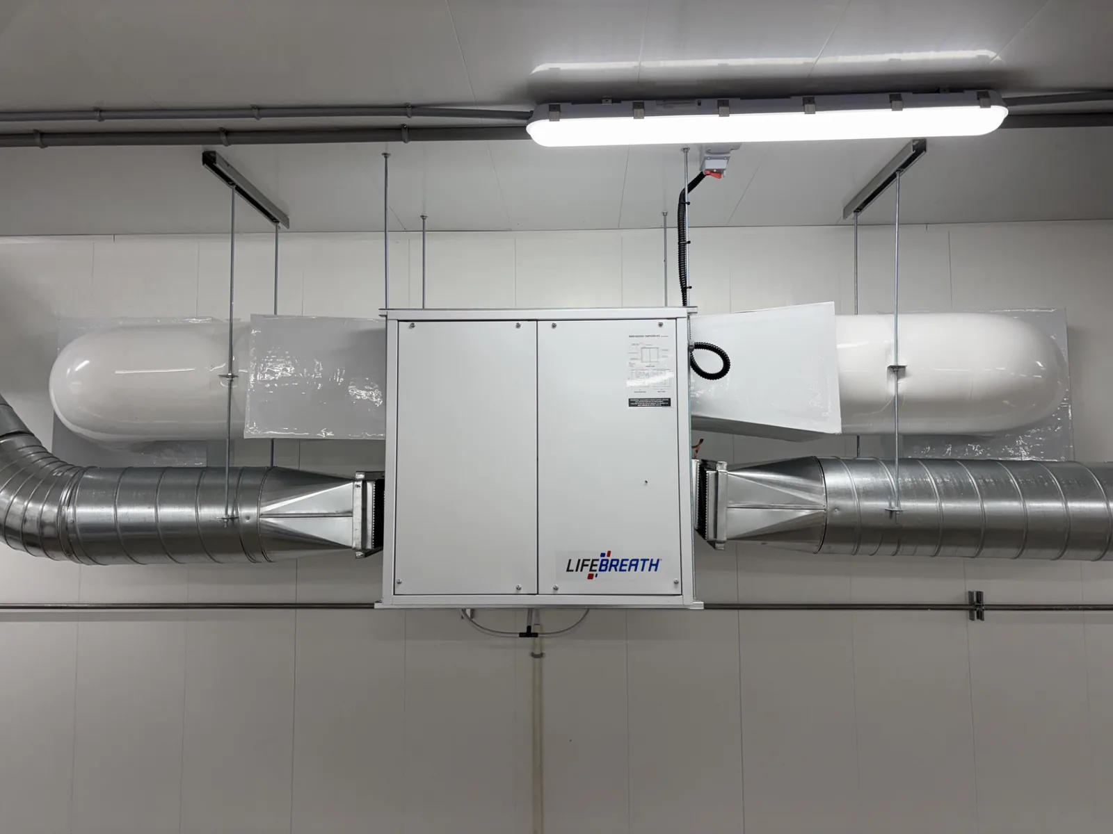 Conduits de ventilation isolés raccordés à un échangeur d'air dans une salle mécanique