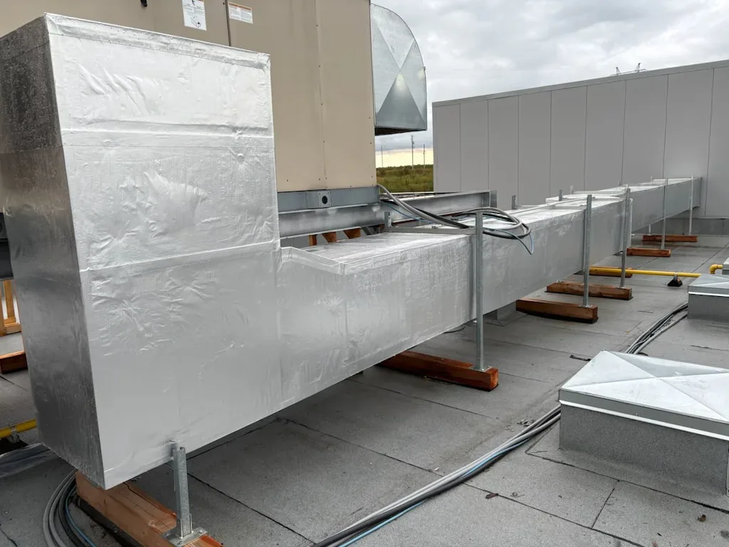 Conduits de ventilation isolés raccordés à un appareil sur une toiture commerciale