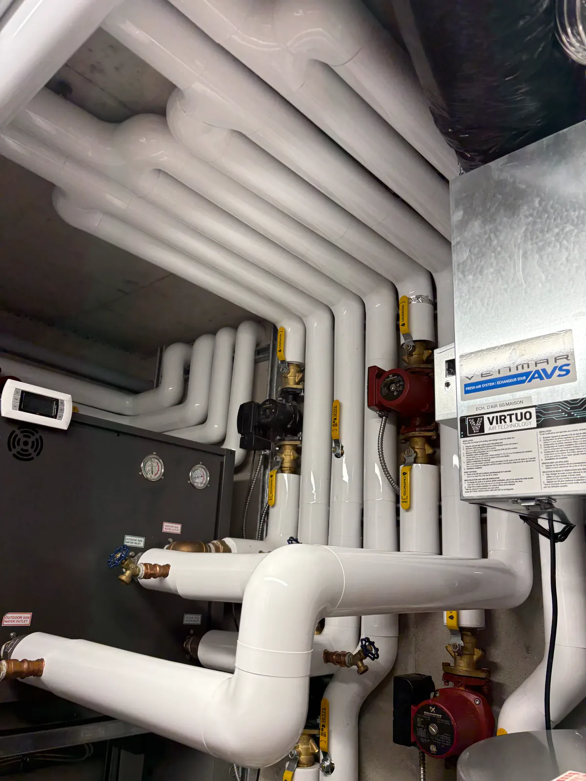 Coudes de tuyauterie intérieure sous une gaine blanche de type PVC
